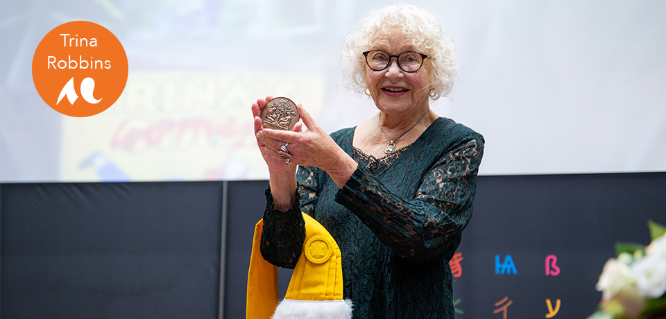 Trina Robbins au centre tenant la médaille de docteure Honoris Causa avec l'écharpe jaune sur le bras droit. ©Gautier Dufau