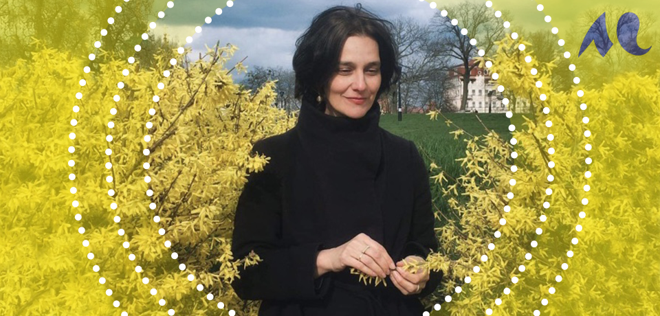 portrait de Katja Petrowskaja en ext&eacute;rieur entour&eacute;e d'arbres en fleurs