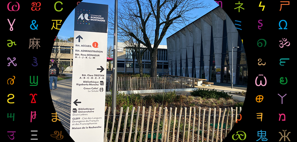 Premier plan, un panneau signal&eacute;tique ; arri&egrave;re plan , le b&acirc;timent Administration et l'amphi 700 de l'universit&eacute;